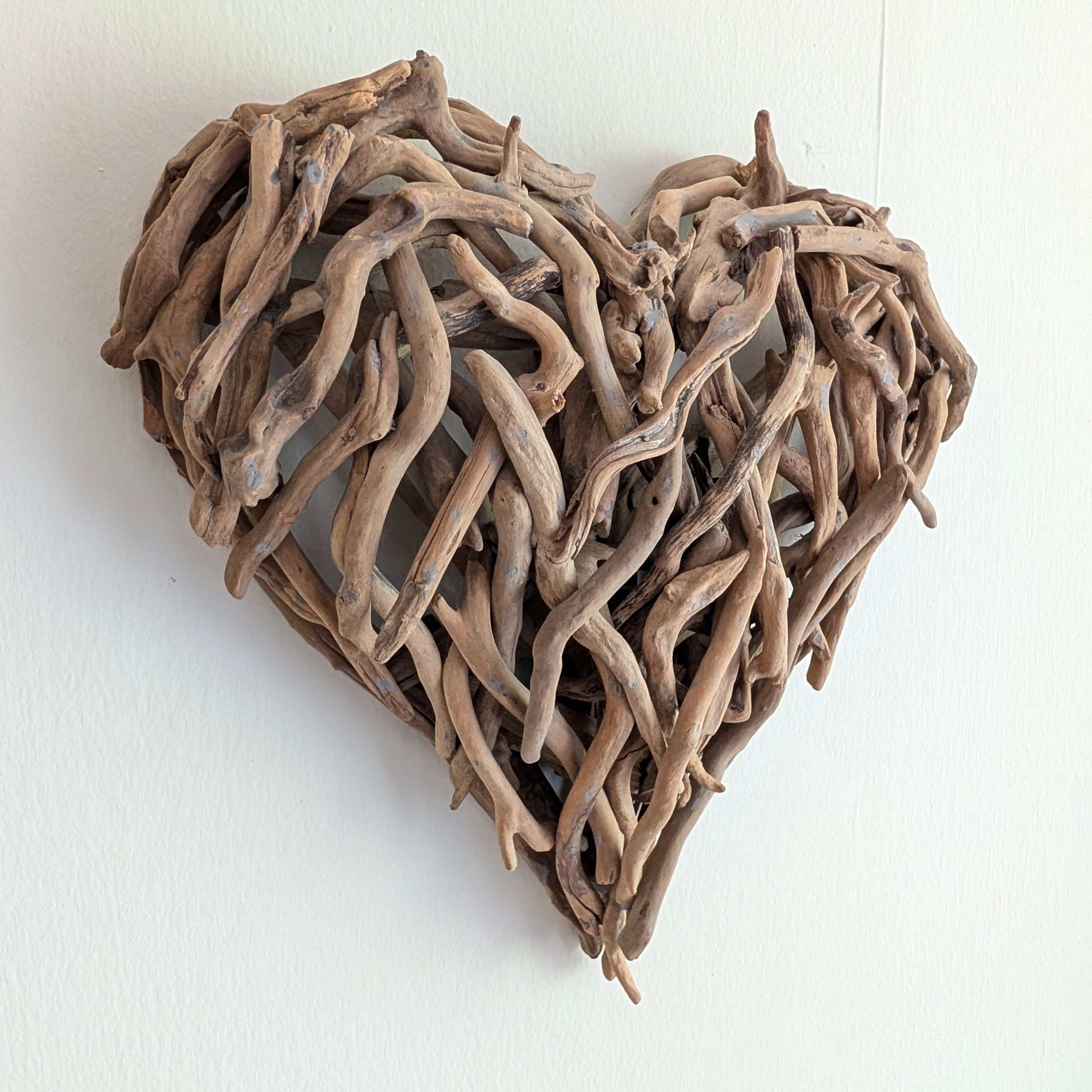 Heart-shaped wall art made of driftwood on a white background