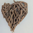 Heart-shaped wall decor made of driftwood on a white background
