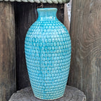Blue textured vase on a wooden surface with a rustic background
