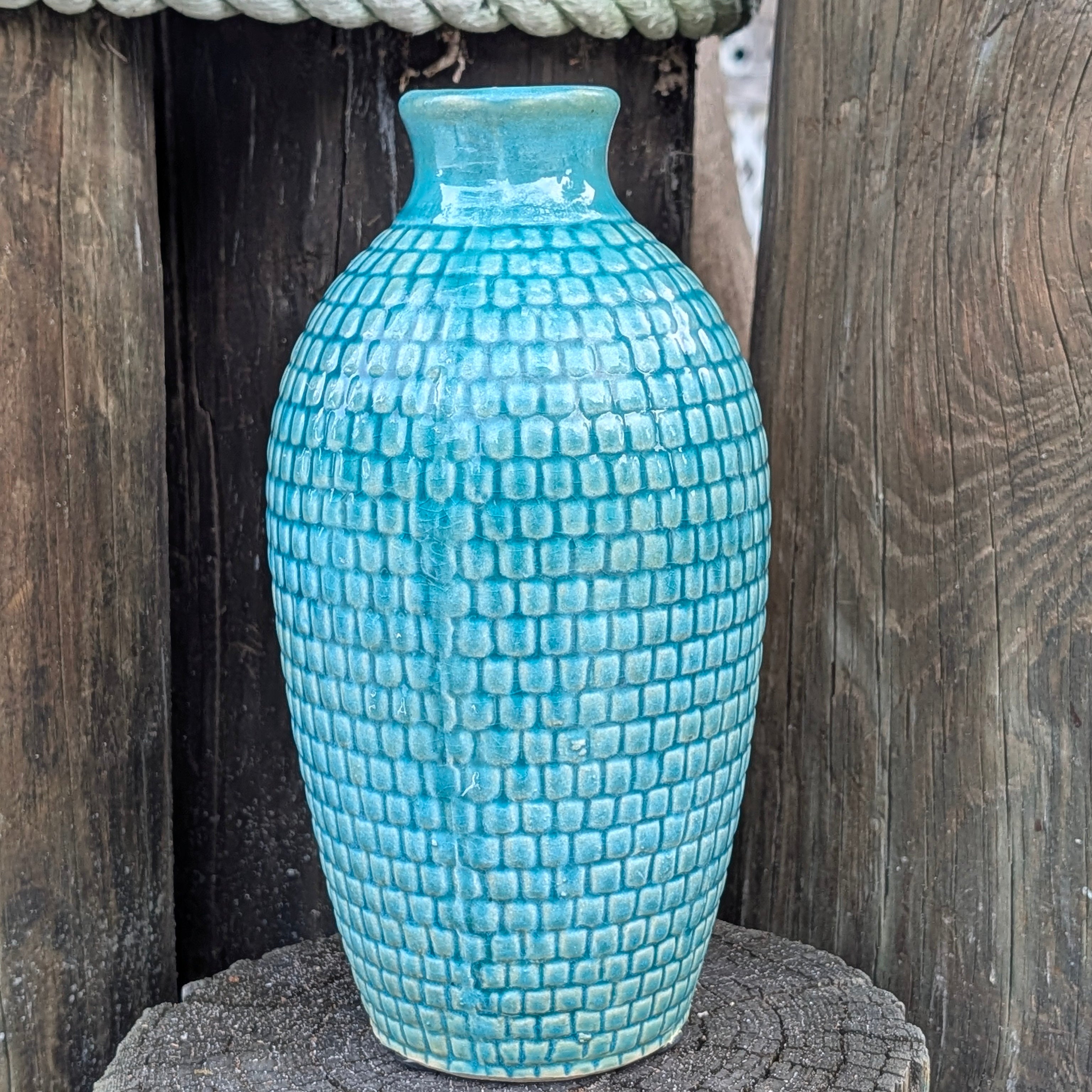 Blue textured vase on a wooden surface with a rustic background