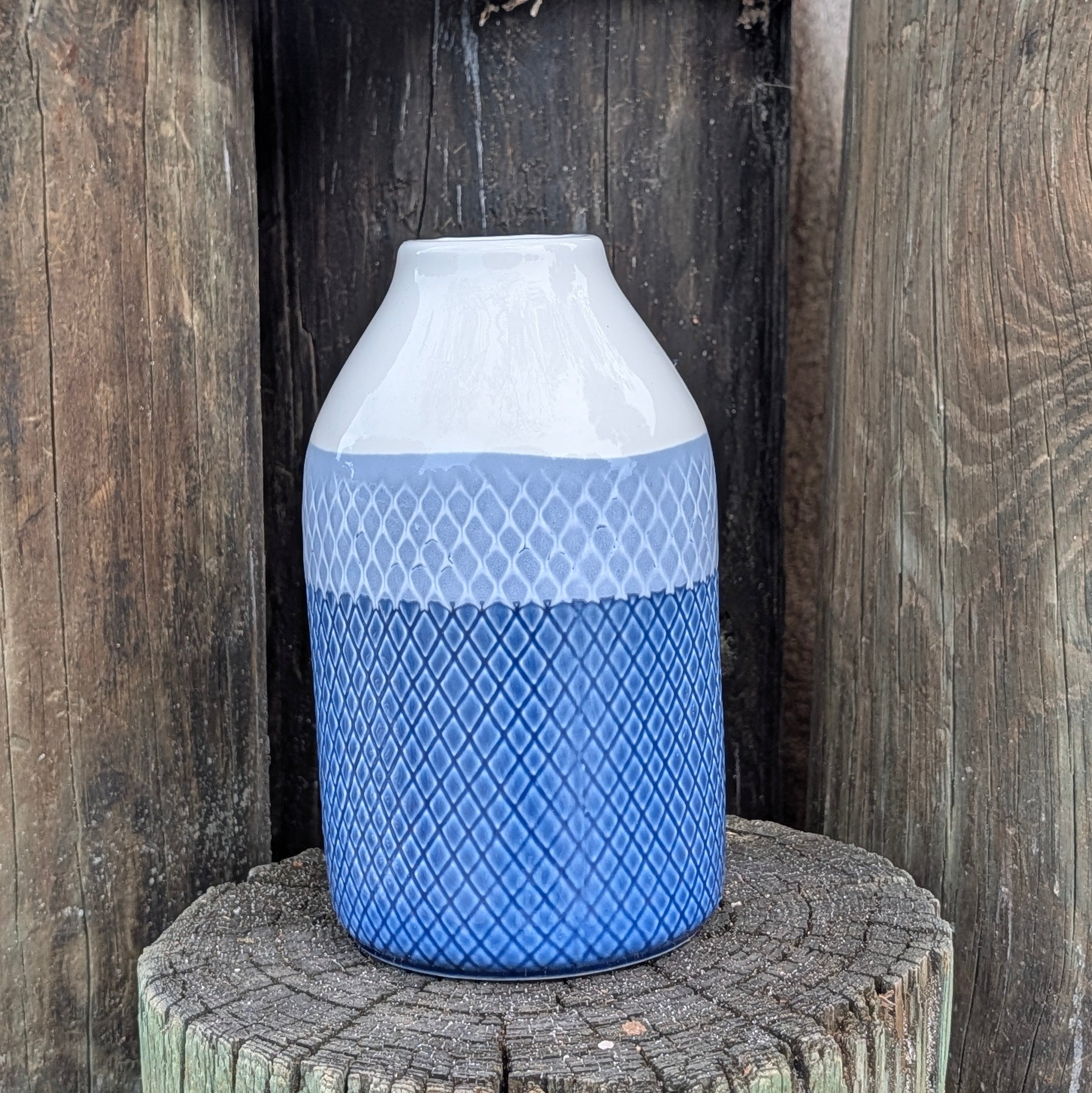 Decorative vase with blue and white pattern on a wooden post