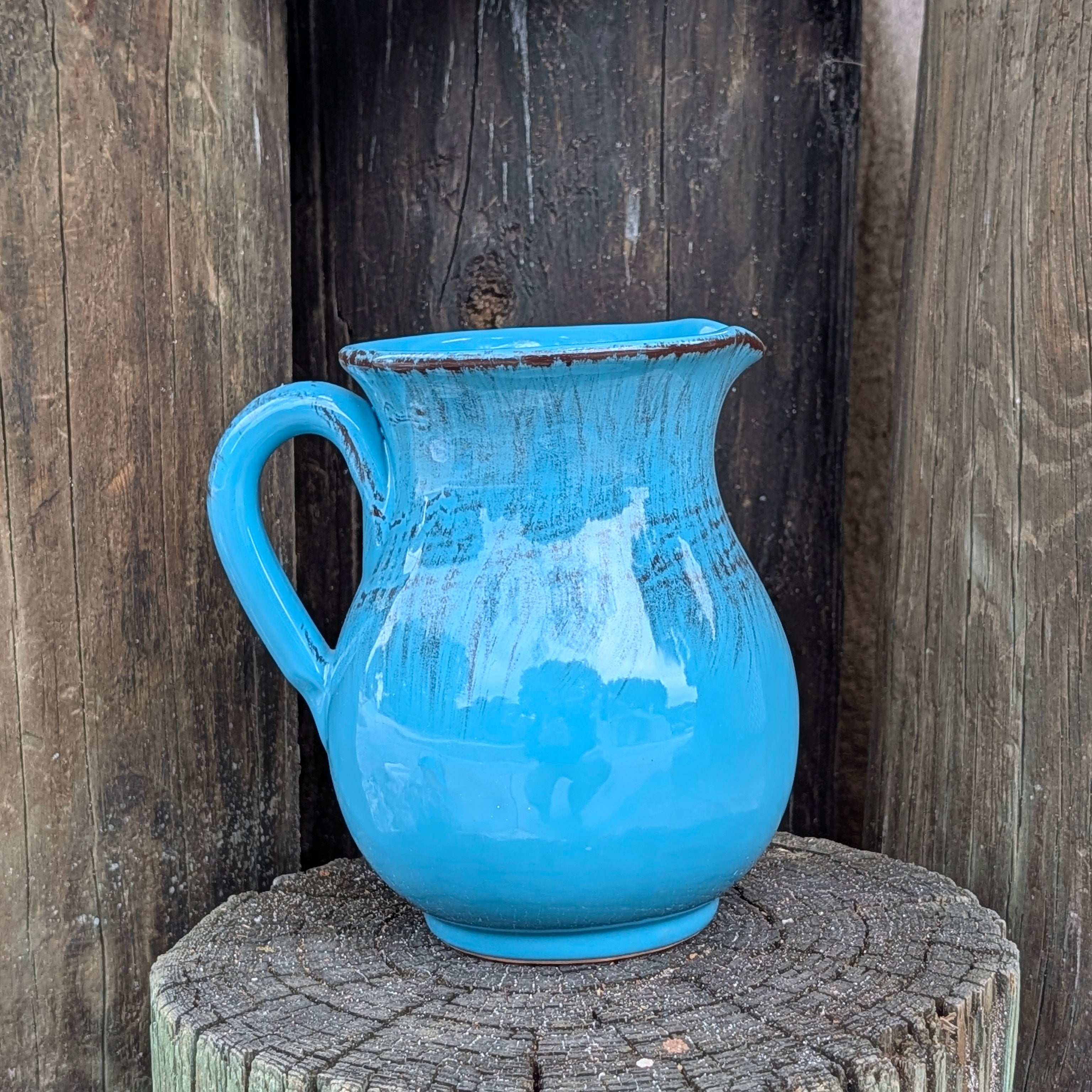 Blue pitcher on a wooden post with a rustic background
