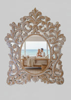 Decorative ornate frame with a distressed finish on a white shelf.