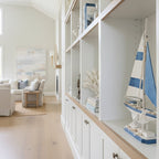 Model sailboat with blue and white sails on a white shelf