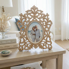 Decorative ornate frame with a distressed finish on a white shelf.