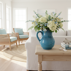 Blue ceramic pitcher with dark markings on a white background