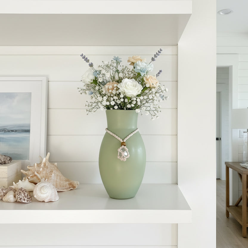 Green vase with a necklace draped over it against a white background